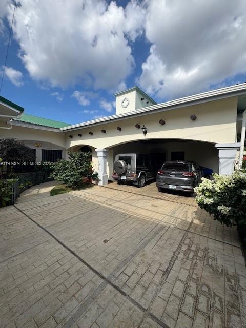 A paved driveway leads to a covered carport attached to a house with a tower — KM 9.5 Carretera Vieja A. Leon, NI Man, NI