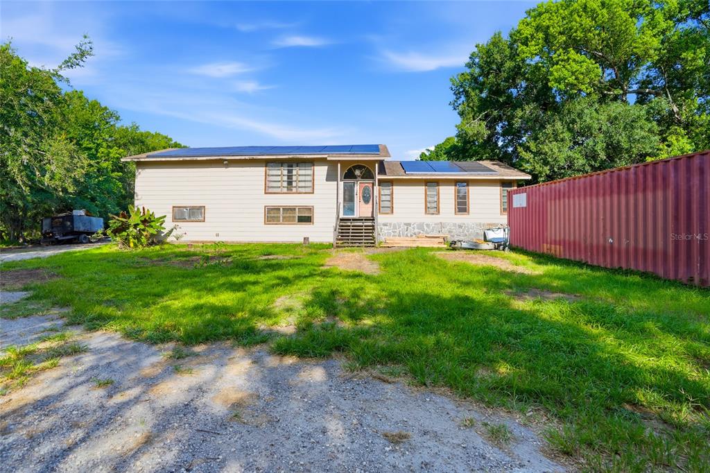 A two-story house with solar panels on the roof sits next to a red shipping container — 2347 BROOKSIDE DRIVE, LUTZ, FL