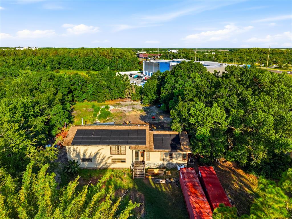 An aerial view of a house with solar panels and two red shipping containers nearby — 2347 BROOKSIDE DRIVE, LUTZ, FL