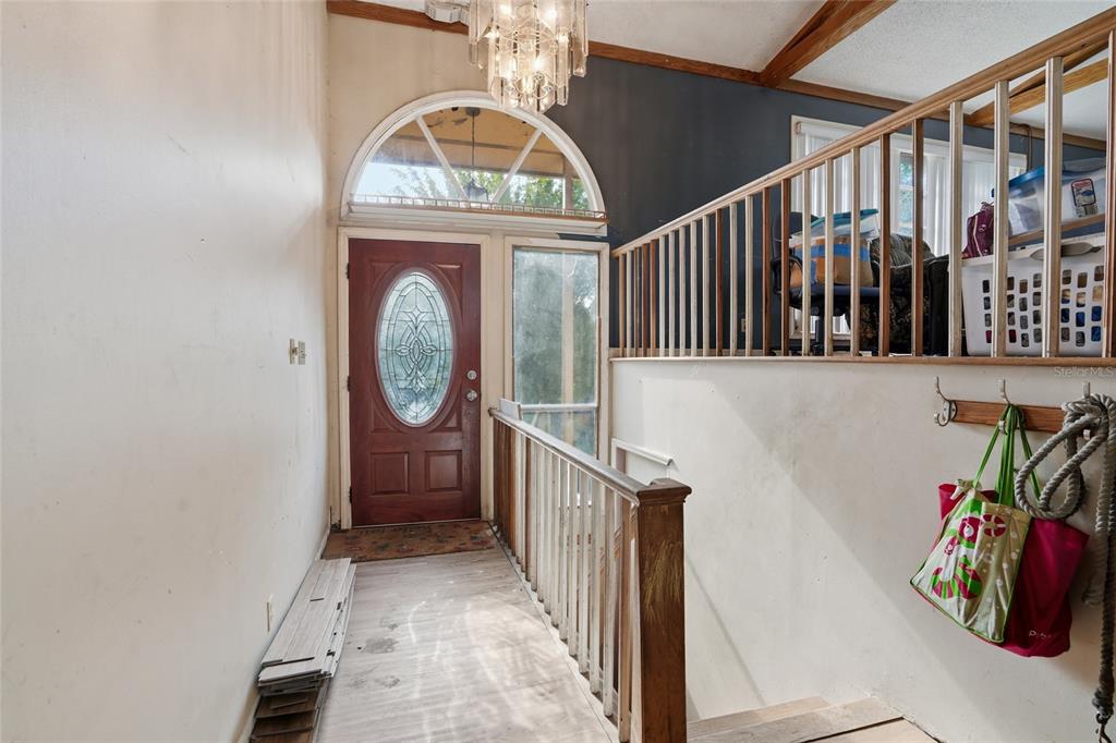 An entryway features a wooden front door, a staircase with railings, and a crystal chandelier — 2347 BROOKSIDE DRIVE, LUTZ, FL