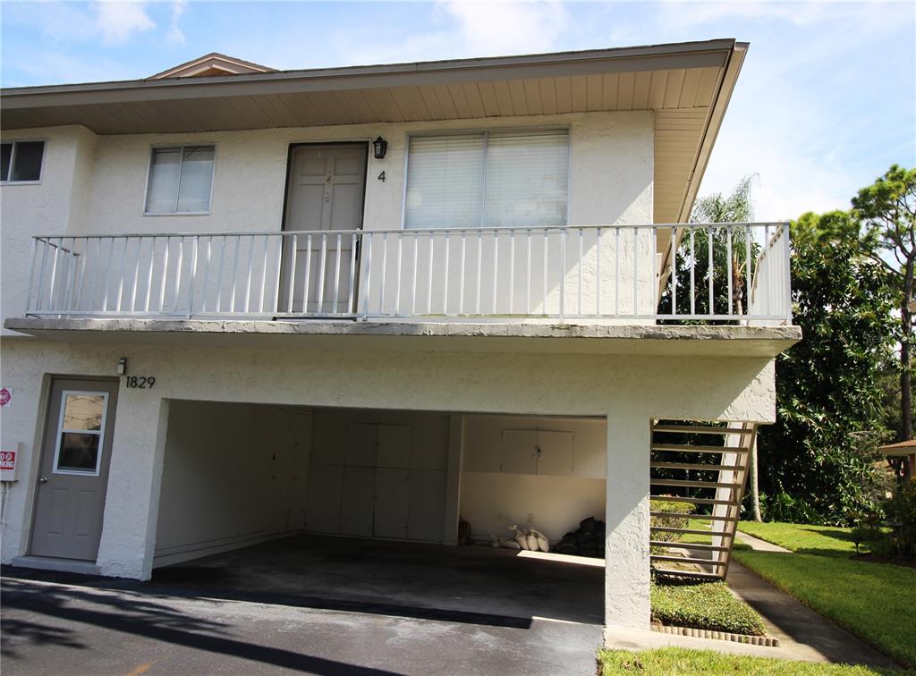 A two-story building features a ground-level carport, an exterior staircase, and an upper-level balcony — 1829 BOUGH AVENUE UNIT 4, CLEARWATER, FL