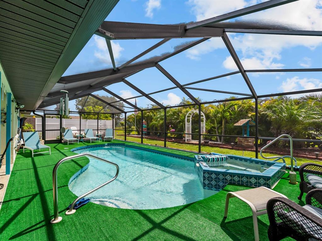 A swimming pool and hot tub are enclosed within a screened-in patio with artificial turf — 120 CUIABA DRIVE, PUNTA GORDA, FL