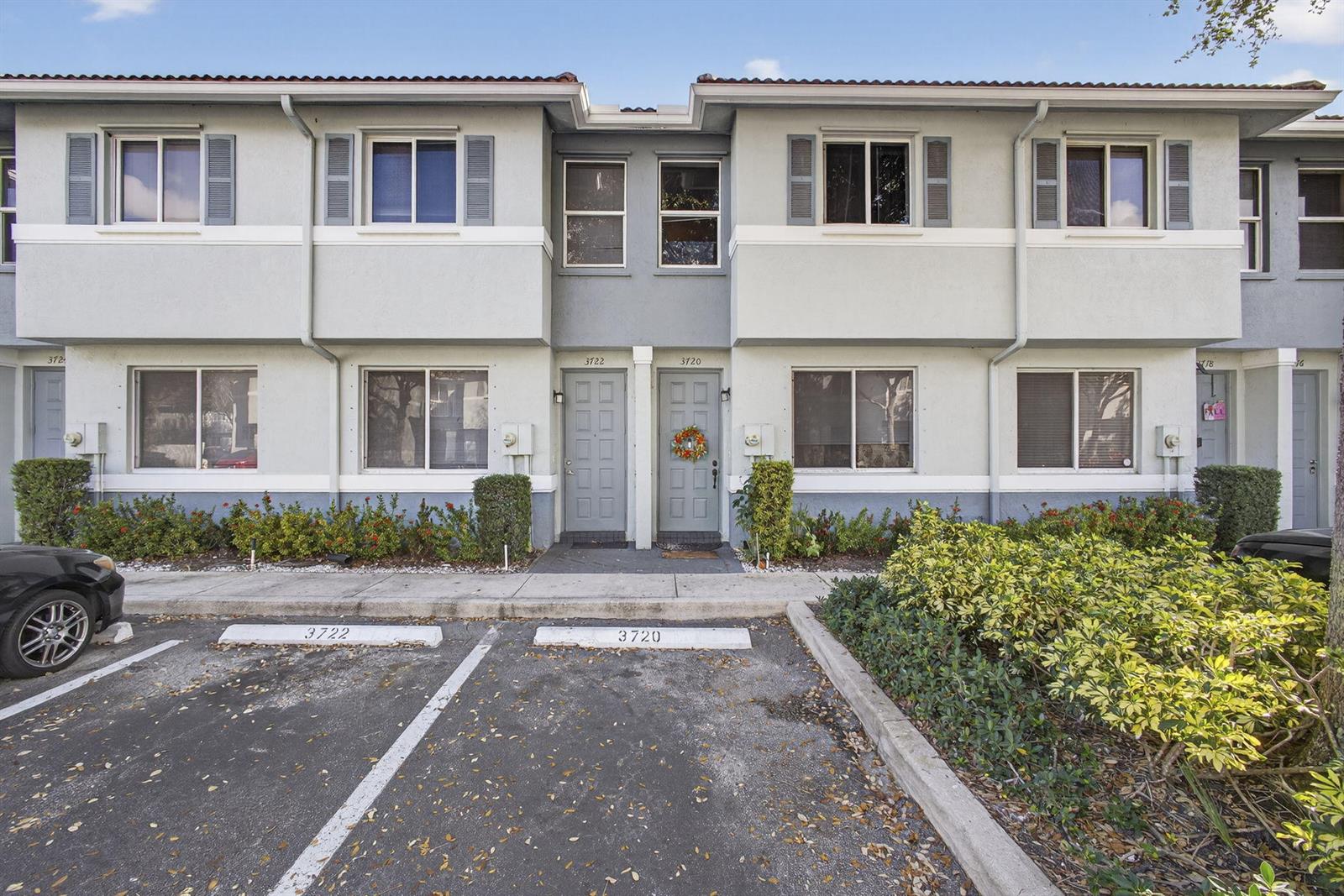 A two-story townhouse exterior features gray siding, designated parking spaces, and a small front garden — 3720 Oleander Terrace, Riviera Beach FL 33404, RIVIERA BEACH, FL