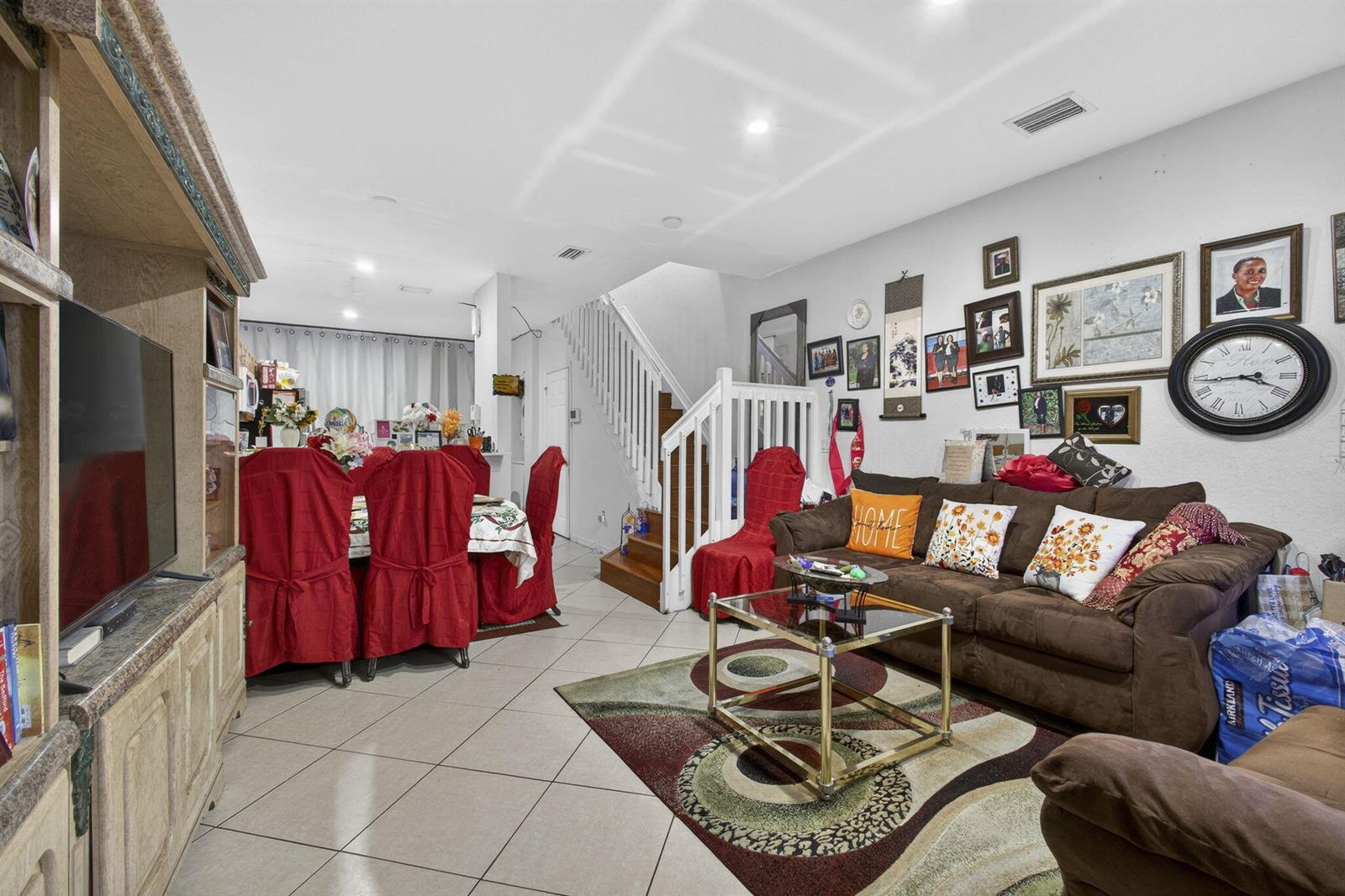 A living room with tile floors, a brown sofa, a dining area, and a staircase — 3720 Oleander Terrace, Riviera Beach FL 33404, RIVIERA BEACH, FL