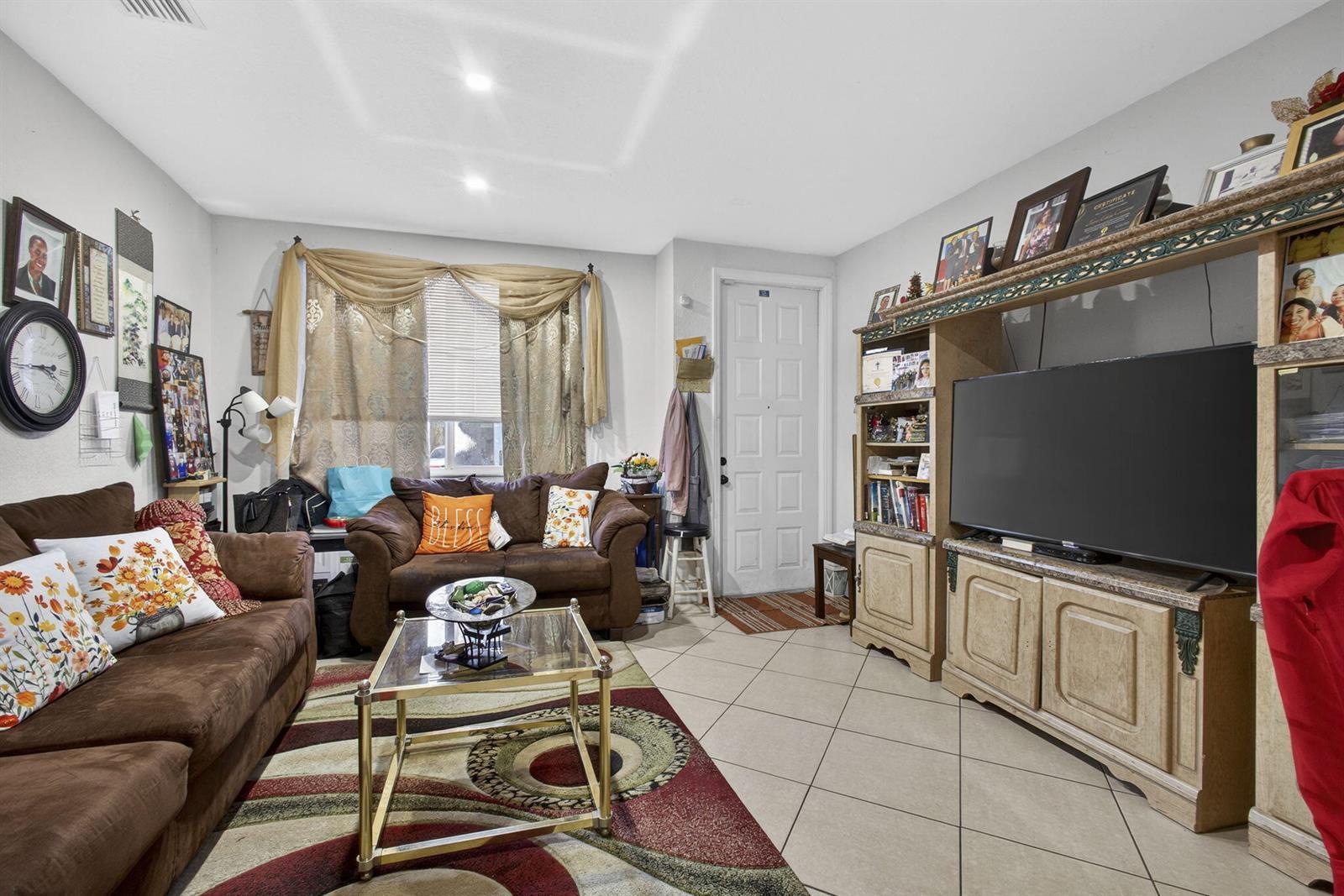 A living room features brown sofas, a glass coffee table, tile flooring, and a media center — 3720 Oleander Terrace, Riviera Beach FL 33404, RIVIERA BEACH, FL