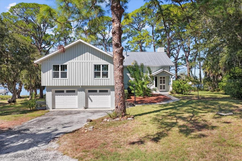 A two-story house with light gray vertical siding and a two-car garage sits outdoors — 16931 SW 133RD STREET, CEDAR KEY, FL