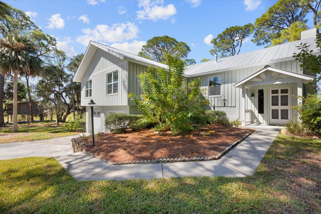 A light gray house with vertical siding, a metal roof, and a landscaped front yard — 16931 SW 133RD STREET, CEDAR KEY, FL