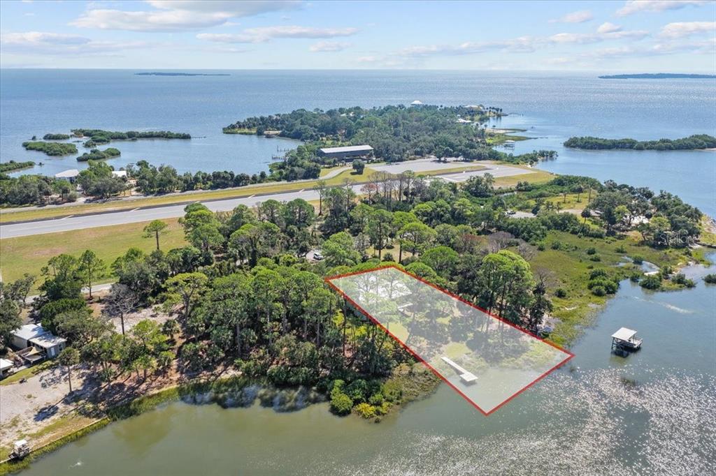 An aerial view shows a rectangular waterfront property lot outlined in red near an airstrip — 16931 SW 133RD STREET, CEDAR KEY, FL