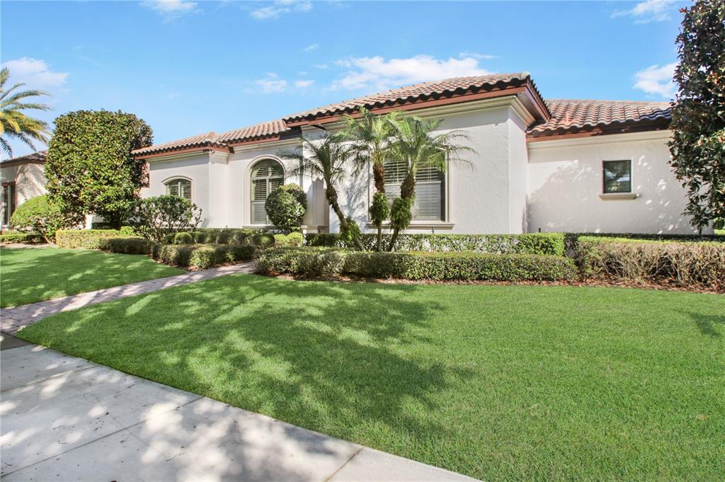 A single-story house with a white stucco exterior, tile roof, and manicured landscaping — 11820 WATERSTONE LOOP DRIVE, WINDERMERE, FL