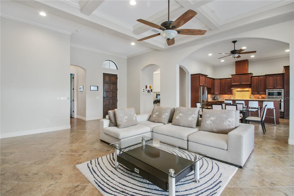 A living room with tile floors, a sectional sofa, and an open kitchen in back — 11820 WATERSTONE LOOP DRIVE, WINDERMERE, FL