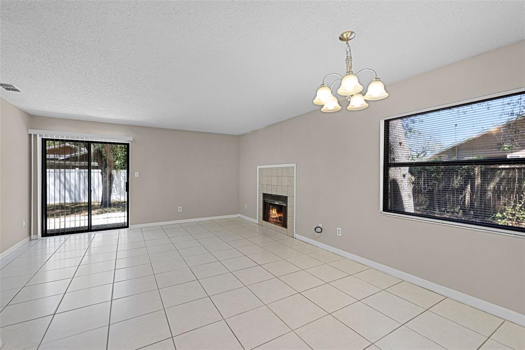 A living room with tile flooring, a fireplace, a chandelier, and sliding glass patio doors — 2530 KAMNIC COURT, WINTER PARK, FL