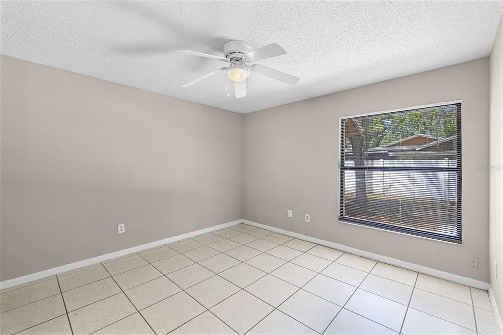 An empty bedroom with beige walls, white tile flooring, and a ceiling fan — 2530 KAMNIC COURT, WINTER PARK, FL