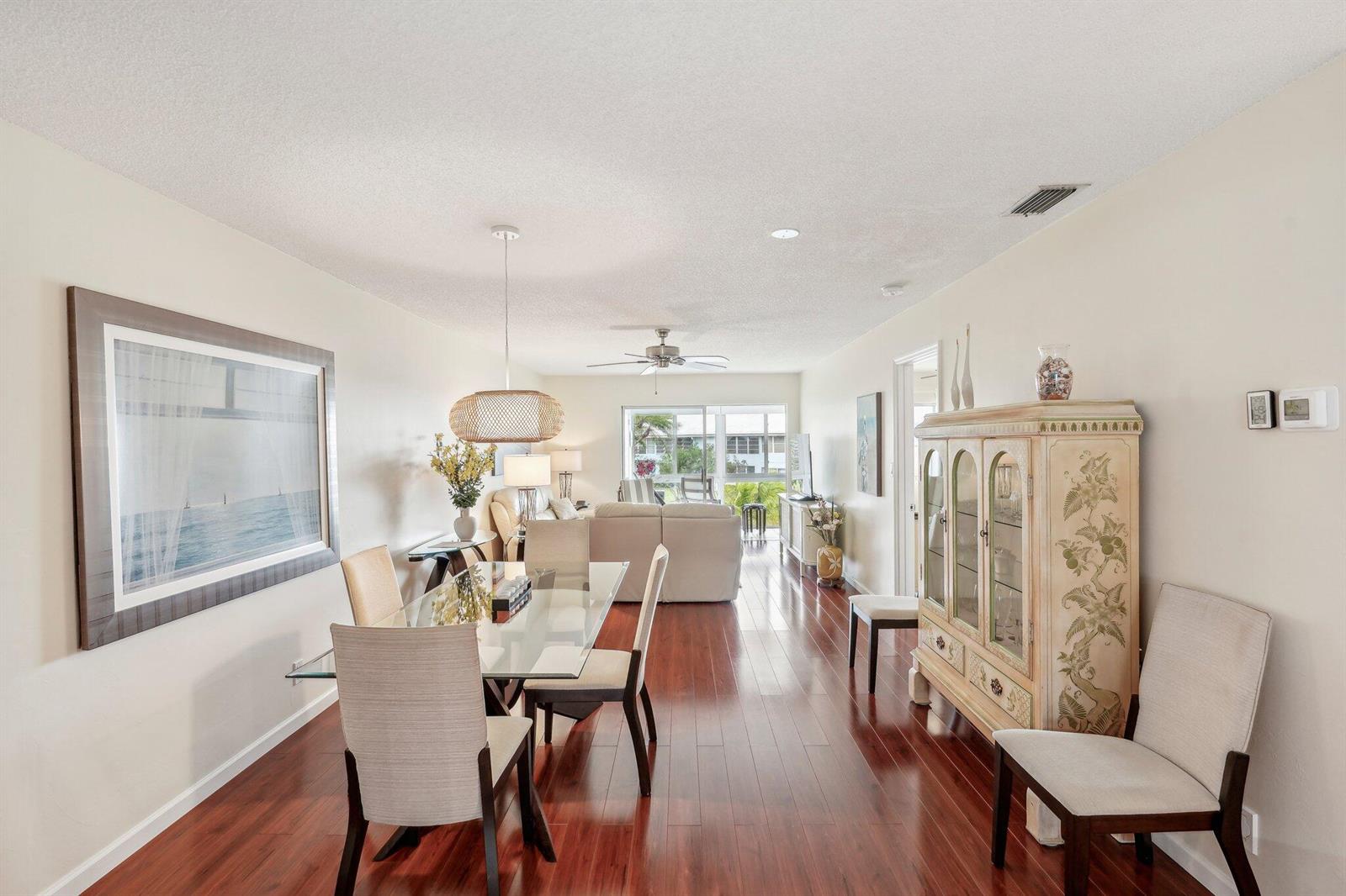 A dining area with a glass table and chairs flows into a living room with hardwood — 5540 N Ocean Boulevard # 212, Ocean Ridge FL 33435, OCEAN RIDGE, FL