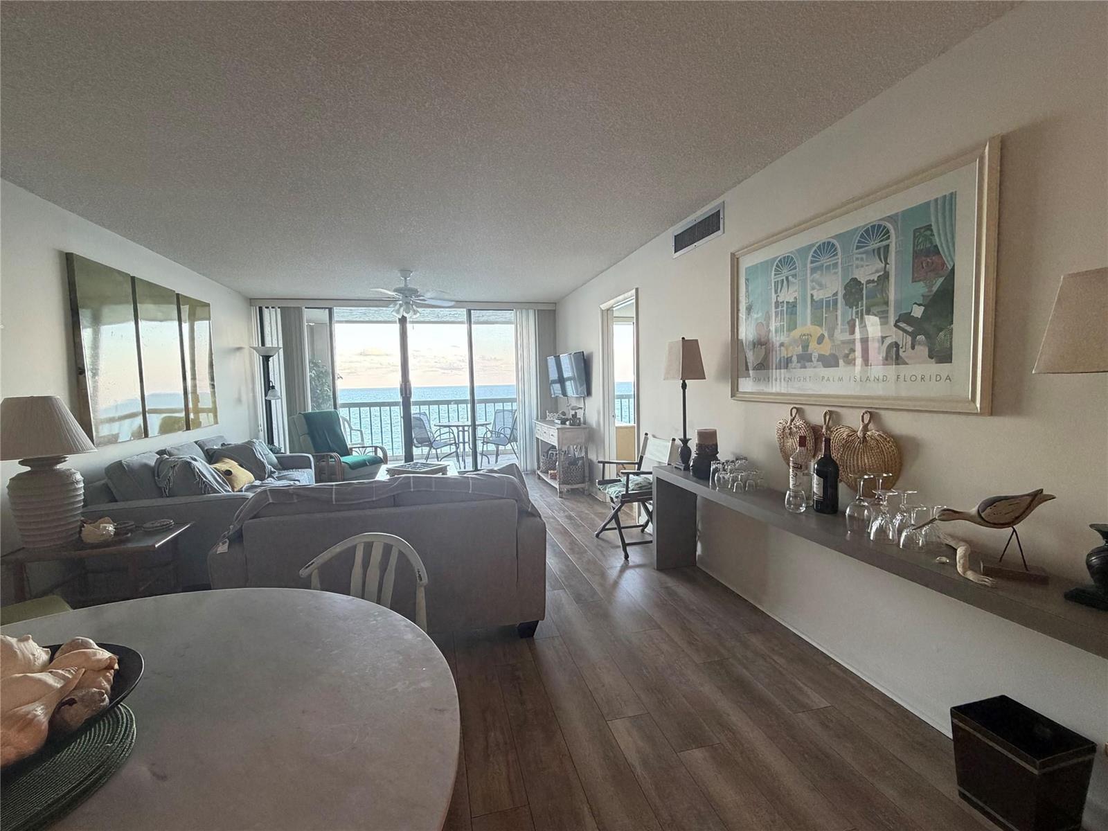 A living room with wood-look flooring, a dining area, and a balcony overlooking the ocean — 10600 S Ocean Drive # 1103, Jensen Beach FL 34957, JENSEN BEACH, FL