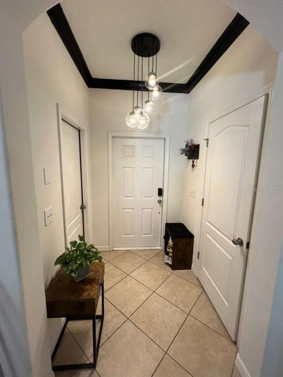 An entryway features tile flooring, a multi-pendant light fixture, a console table, and white doors — 6453 SEDGEFORD DRIVE, LAKELAND, FL
