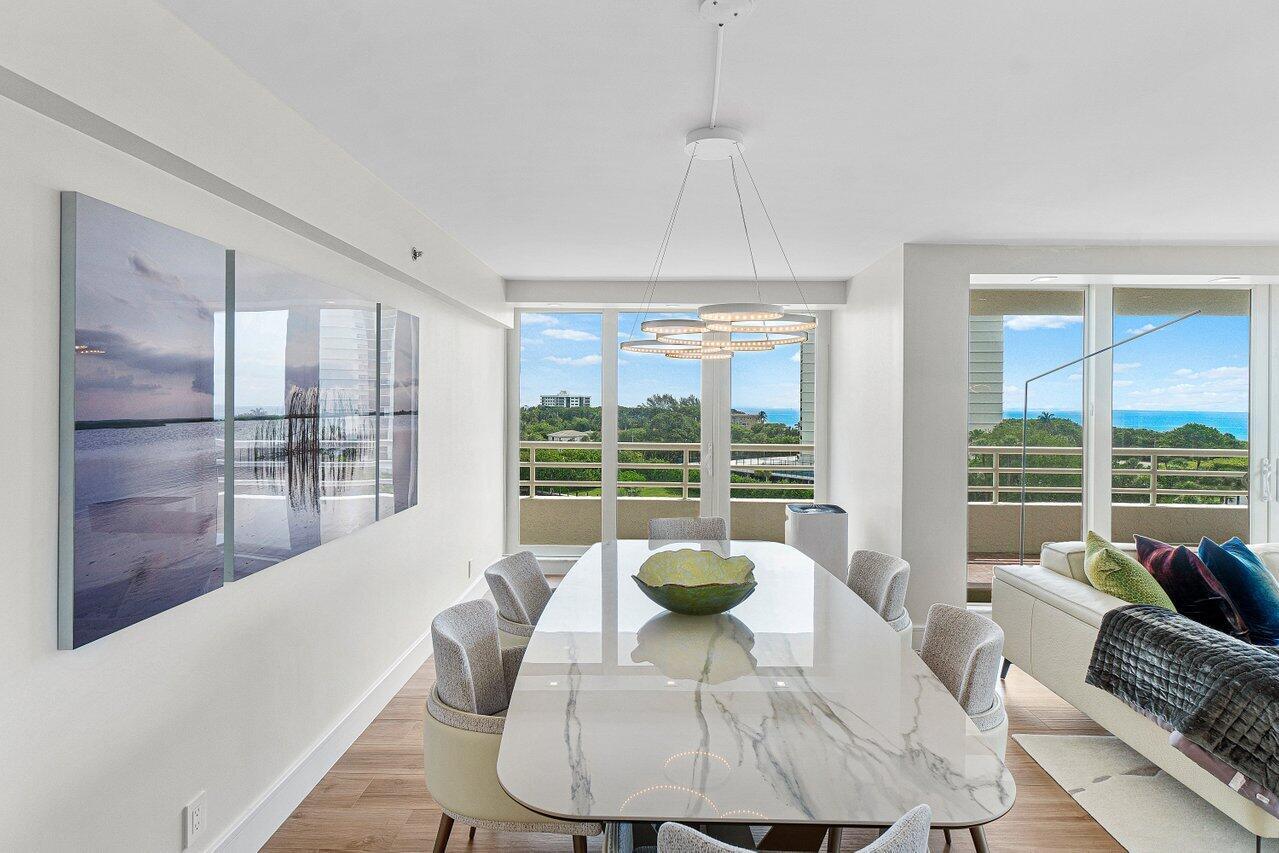 A dining room features a marble table, modern chandelier, and large windows overlooking the ocean — 4201 N Ocean Boulevard # 601, Boca Raton FL 33431, BOCA RATON, FL