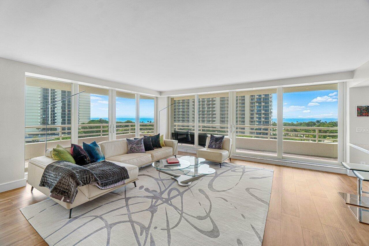 A bright living room features a white sectional sofa, glass coffee table, and floor-to-ceiling windows — 4201 N Ocean Boulevard # 601, Boca Raton FL 33431, BOCA RATON, FL