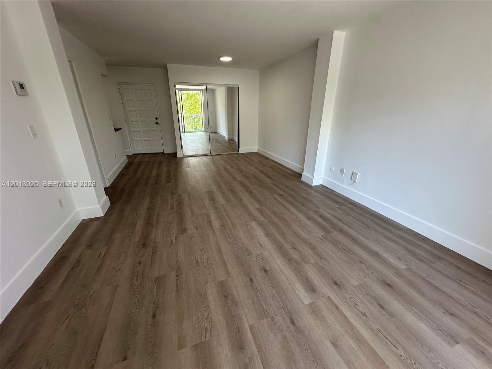 An empty room features light wood-look flooring, white walls, and a mirrored closet — 777 NE 62nd St # C306, Miami FL 33138, MIAMI, FL