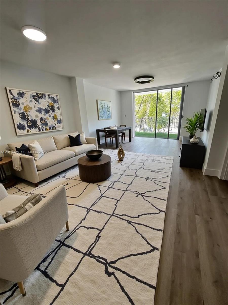 A living room features a beige sofa, a patterned area rug, and a dining table — 777 NE 62nd St # C306, Miami FL 33138, MIAMI, FL