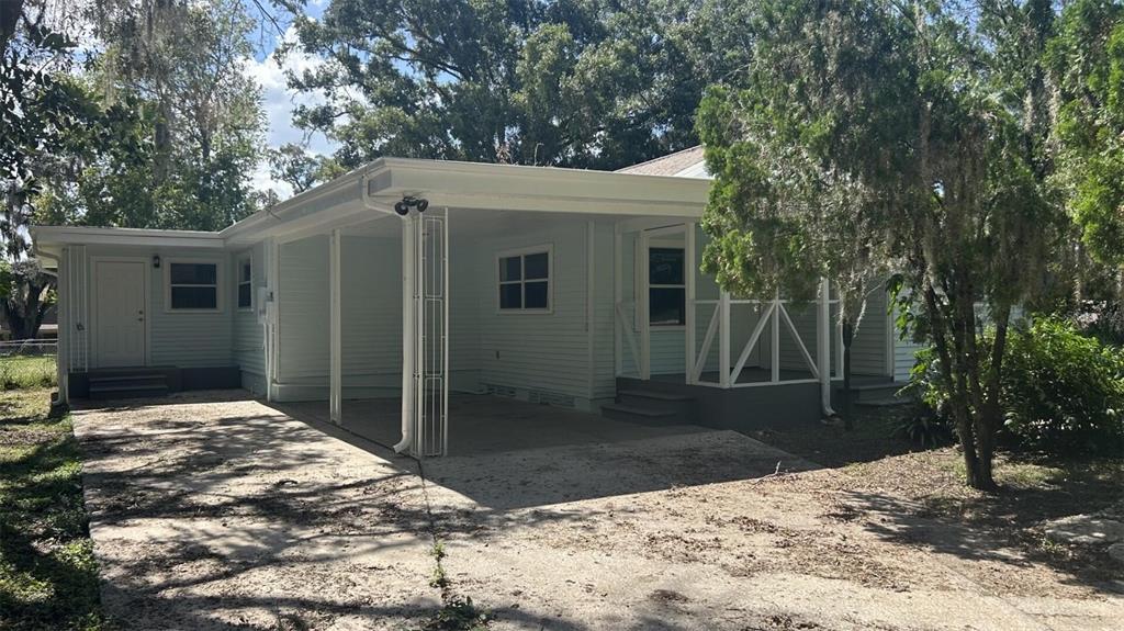 A light blue house features a concrete carport, a screened-in porch, and a gravel driveway — 4316 CLEWIS AVENUE, TAMPA, FL