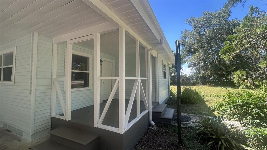 A light blue house features a white-framed screened-in porch with gray painted steps — 4316 CLEWIS AVENUE, TAMPA, FL