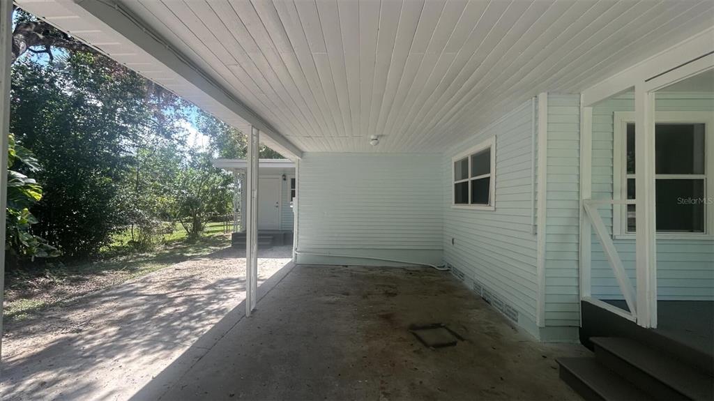 A covered concrete carport sits beside the light blue siding of a house — 4316 CLEWIS AVENUE, TAMPA, FL