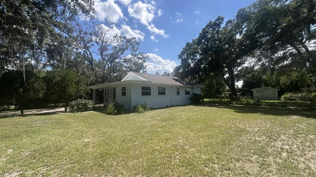 A light-colored, single-story house with a covered porch sits on a large, grassy lot — 4316 CLEWIS AVENUE, TAMPA, FL