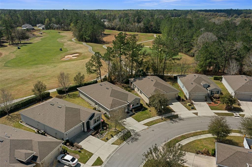 An aerial view shows several suburban houses situated along a golf course and wooded area — 17807 GARSALASO CIRCLE, BROOKSVILLE, FL