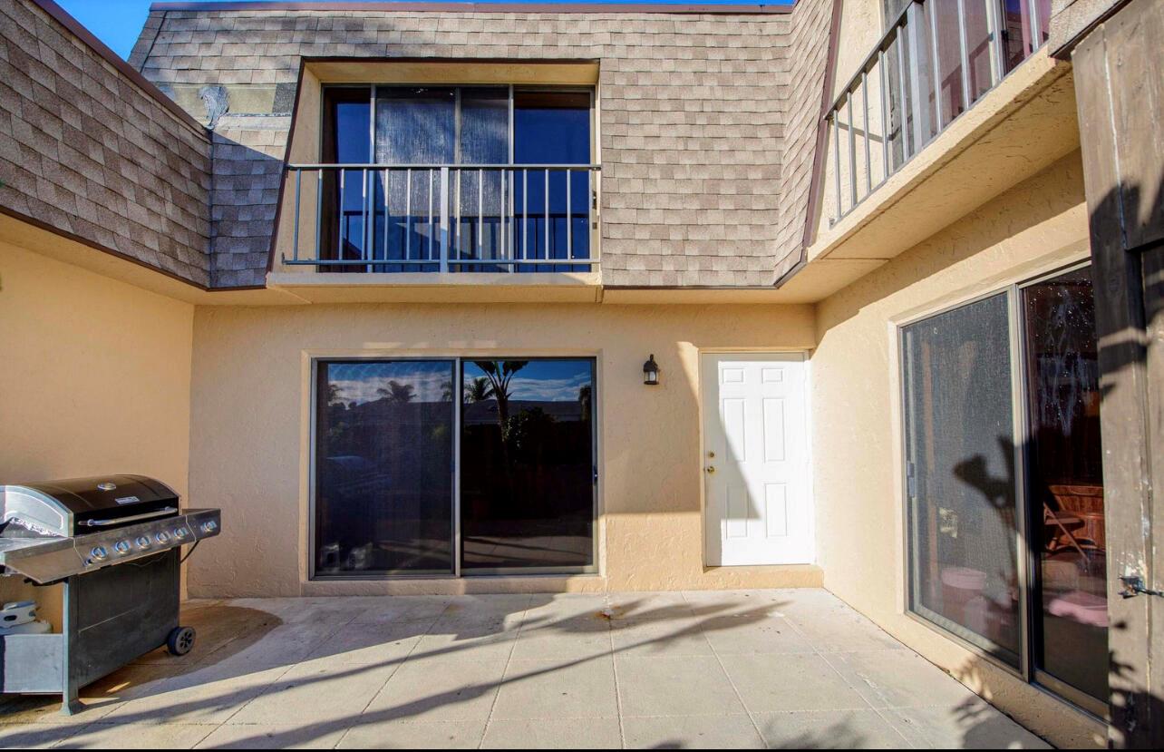 A paved patio area features a stainless steel grill, a white door, and sliding glass doors — 4101 N Waterview Circle # a, Palm Springs FL 33461, PALM SPRINGS, FL