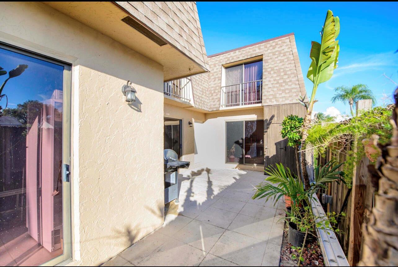 A paved patio area sits between two sections of a two-story house with sliding doors — 4101 N Waterview Circle # a, Palm Springs FL 33461, PALM SPRINGS, FL