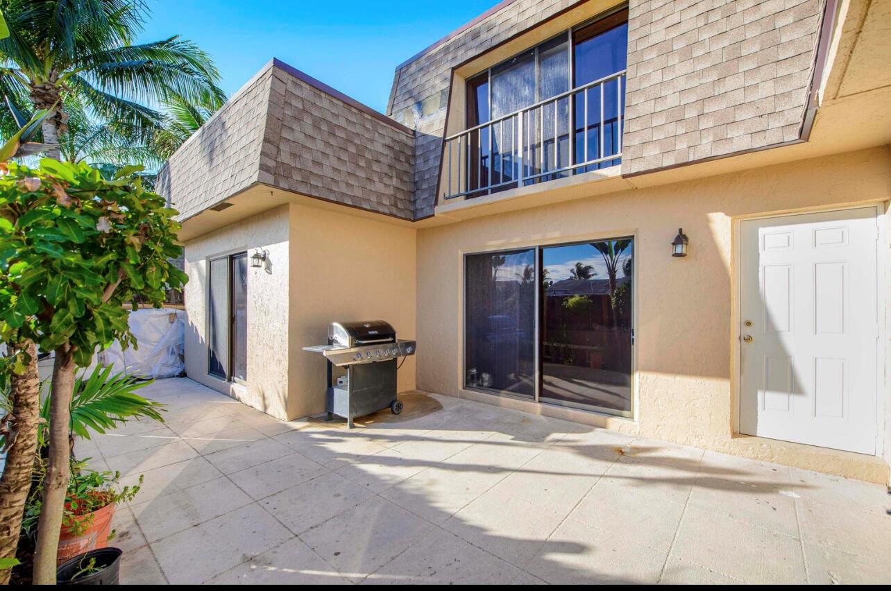 A paved patio area features a gas grill, sliding glass doors, and a second-story balcony — 4101 N Waterview Circle # a, Palm Springs FL 33461, PALM SPRINGS, FL