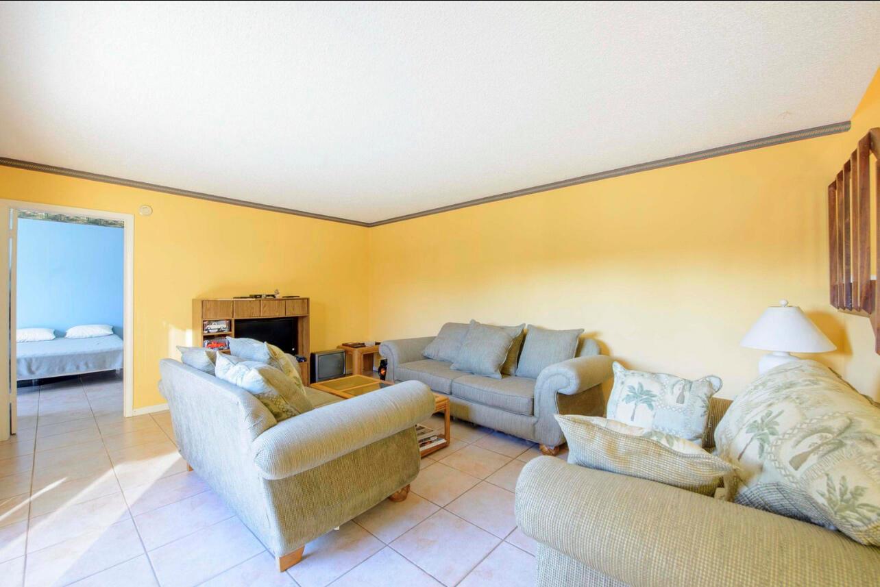 A living room with yellow walls, tile flooring, and three upholstered sofas — 4101 N Waterview Circle # a, Palm Springs FL 33461, PALM SPRINGS, FL