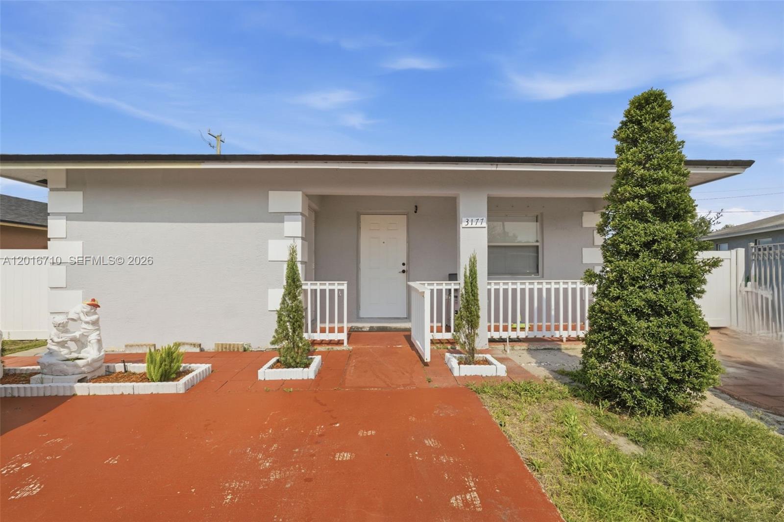 A single-story house features a gray exterior, white trim, a red driveway, and a front porch — 3177 NW 75th Way, Hollywood FL 33024, HOLLYWOOD, FL