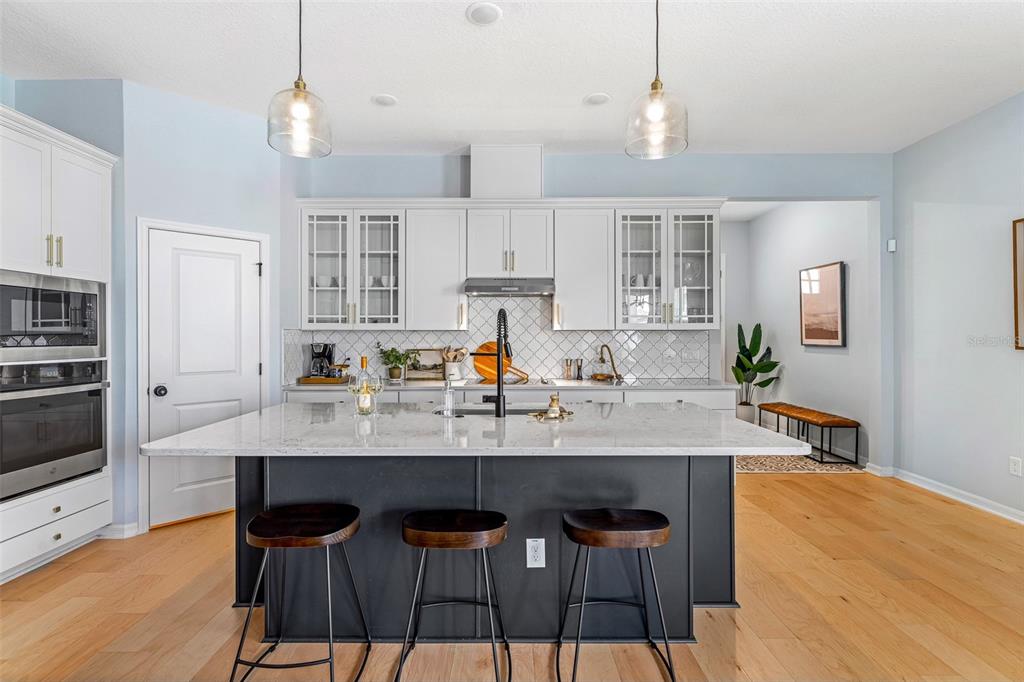 A modern kitchen features a dark island with bar stools, white cabinetry, and light flooring — 798 MIDDLETON STREET, DEBARY, FL