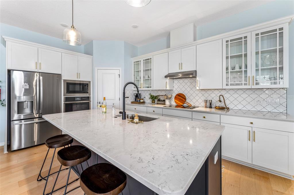A modern kitchen features a large quartz island, white cabinetry, and stainless steel appliances — 798 MIDDLETON STREET, DEBARY, FL