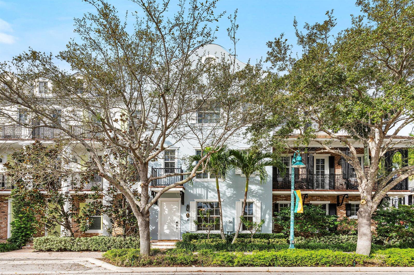 A three-story light blue townhouse with a white front door and wrought-iron balconies — 343 E Cannery Row Circle, Delray Beach FL 33444, DELRAY BEACH, FL
