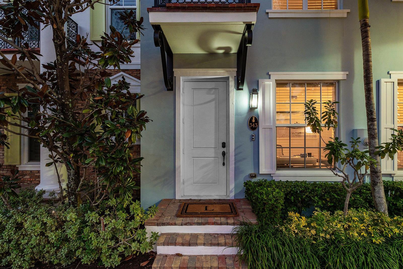 The exterior of a light blue house features a white front door and brick steps — 343 E Cannery Row Circle, Delray Beach FL 33444, DELRAY BEACH, FL