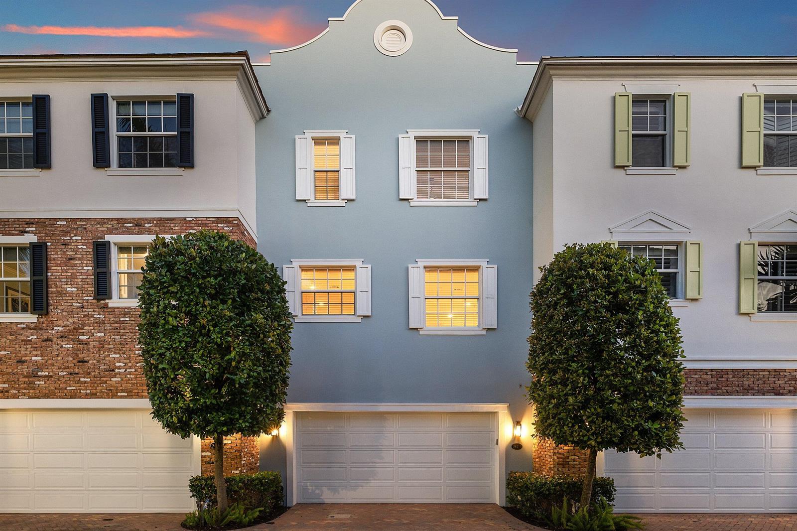 A light blue townhouse exterior features a two-car garage and symmetrical windows with shutters — 343 E Cannery Row Circle, Delray Beach FL 33444, DELRAY BEACH, FL