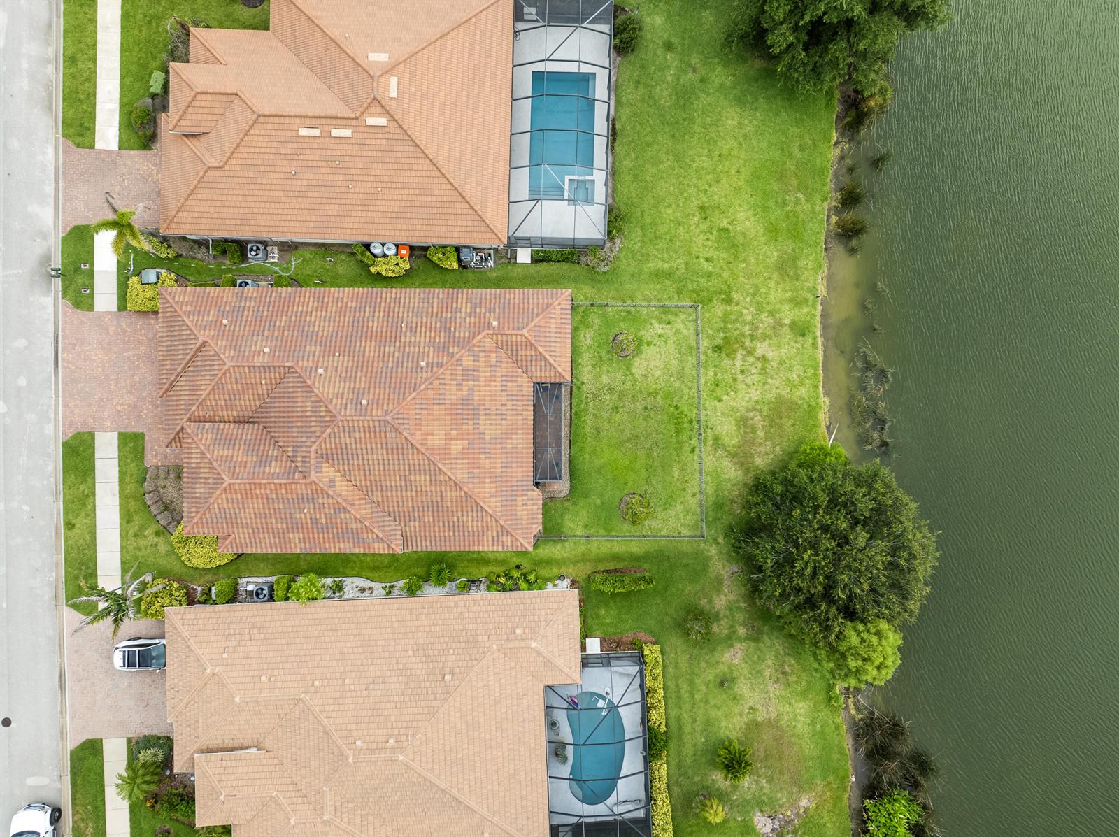 Aerial view of three suburban houses with pools and backyards bordering a lake — 1774 Belmont Circle SW, Vero Beach FL 32968, VERO BEACH, FL