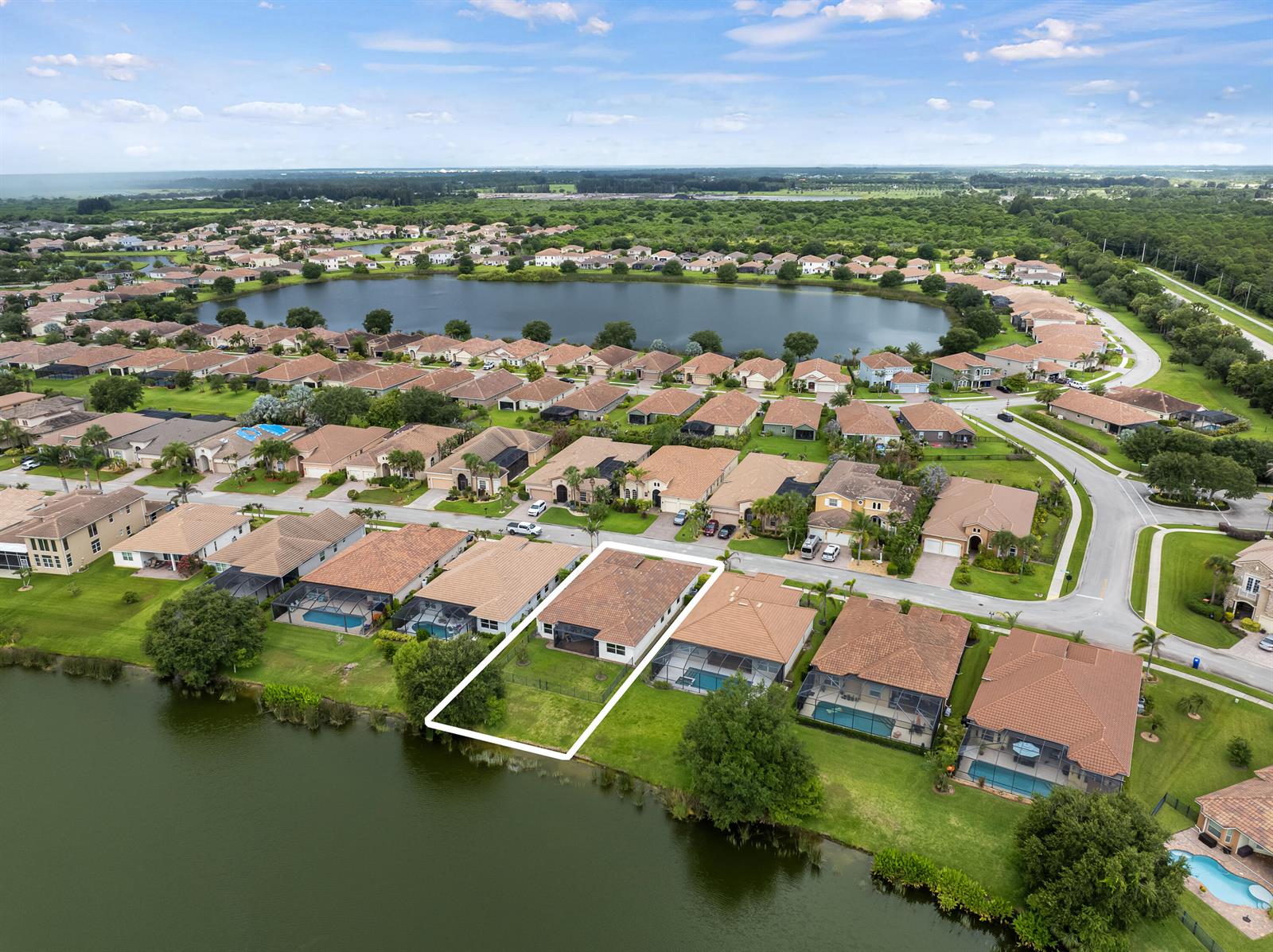 An aerial view shows a residential neighborhood with a highlighted house bordering a lake — 1774 Belmont Circle SW, Vero Beach FL 32968, VERO BEACH, FL