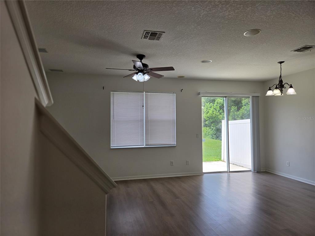 A living room with wood-look flooring, a ceiling fan, a window, and sliding glass doors — 3659 SOARING LANE, SANFORD, FL