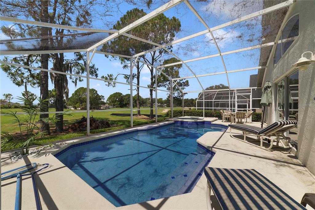 A screened-in swimming pool and spa overlook a golf course on a sunny day — 2135 MALLORY CIRCLE, HAINES CITY, FL