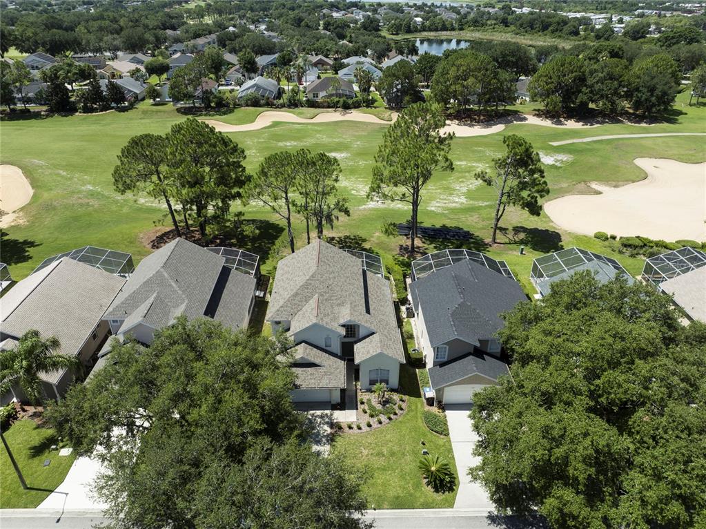 An aerial view shows three suburban houses with screened lanais bordering a golf course — 2135 MALLORY CIRCLE, HAINES CITY, FL