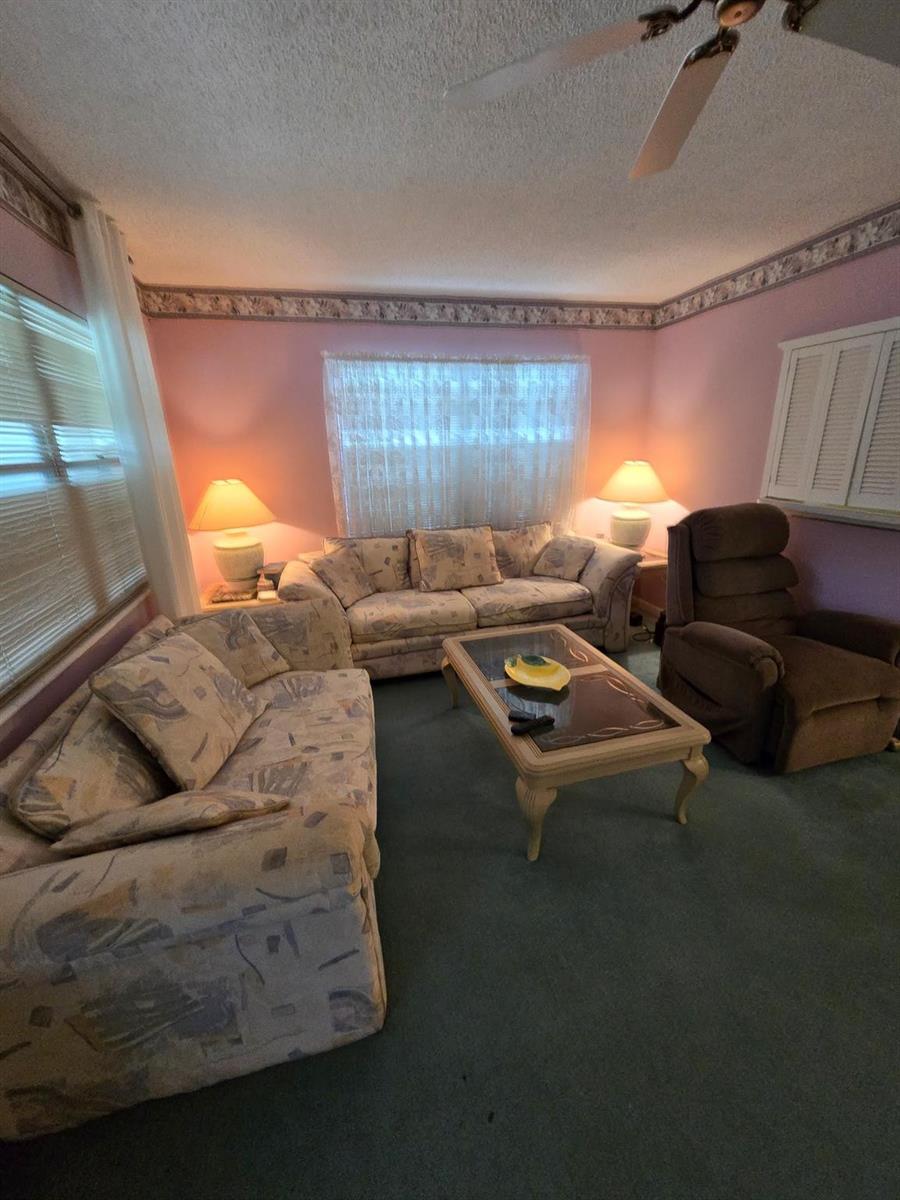 A living room features pink walls, patterned sofas, a brown recliner, and a coffee table — 456 Tilford U # 456, Deerfield Beach FL 33442, DEERFIELD BEACH, FL