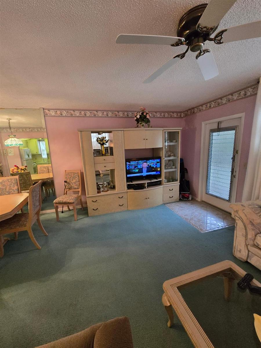 A living room with green carpet, a large entertainment center, and a ceiling fan — 456 Tilford U # 456, Deerfield Beach FL 33442, DEERFIELD BEACH, FL