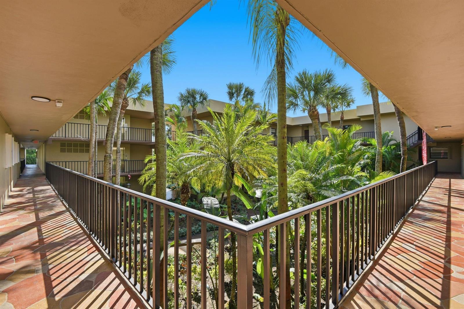 An outdoor walkway overlooks a lush, palm-filled courtyard at a multi-story apartment complex — 10875 SW 112th Avenue # 202, Miami FL 33176, MIAMI, FL
