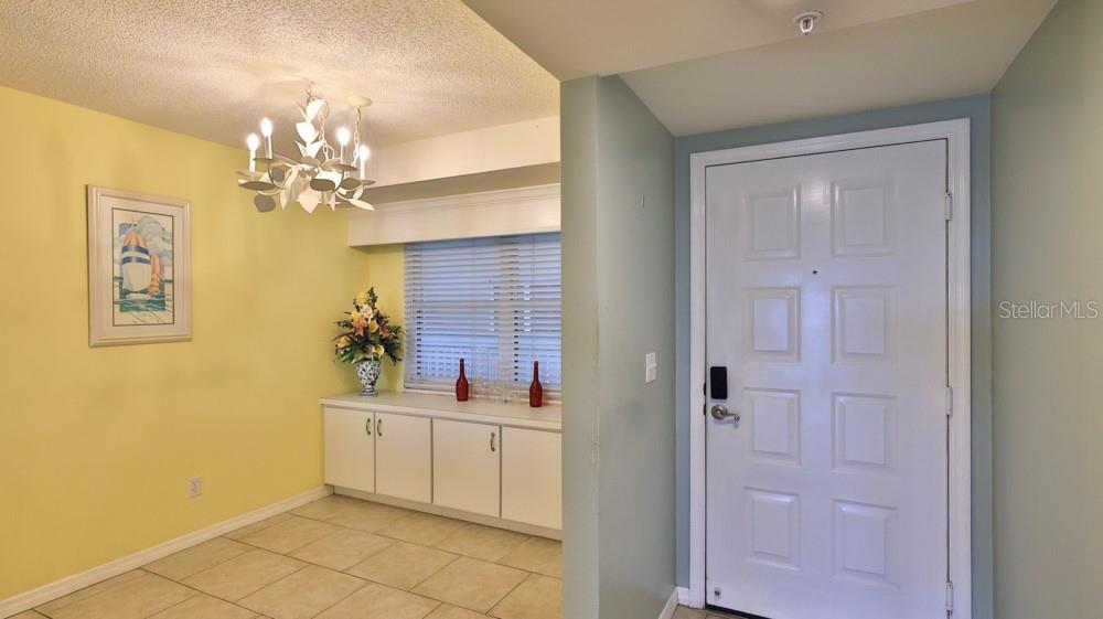 An entryway features a yellow wall, a white cabinet, a chandelier, and a white door — 4 OCEANS WEST BOULEVARD UNIT 508D, DAYTONA BEACH SHORES, FL