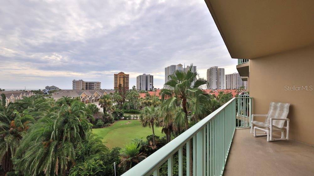 A balcony with a light-colored chair overlooks a golf course and distant high-rise buildings — 4 OCEANS WEST BOULEVARD UNIT 508D, DAYTONA BEACH SHORES, FL