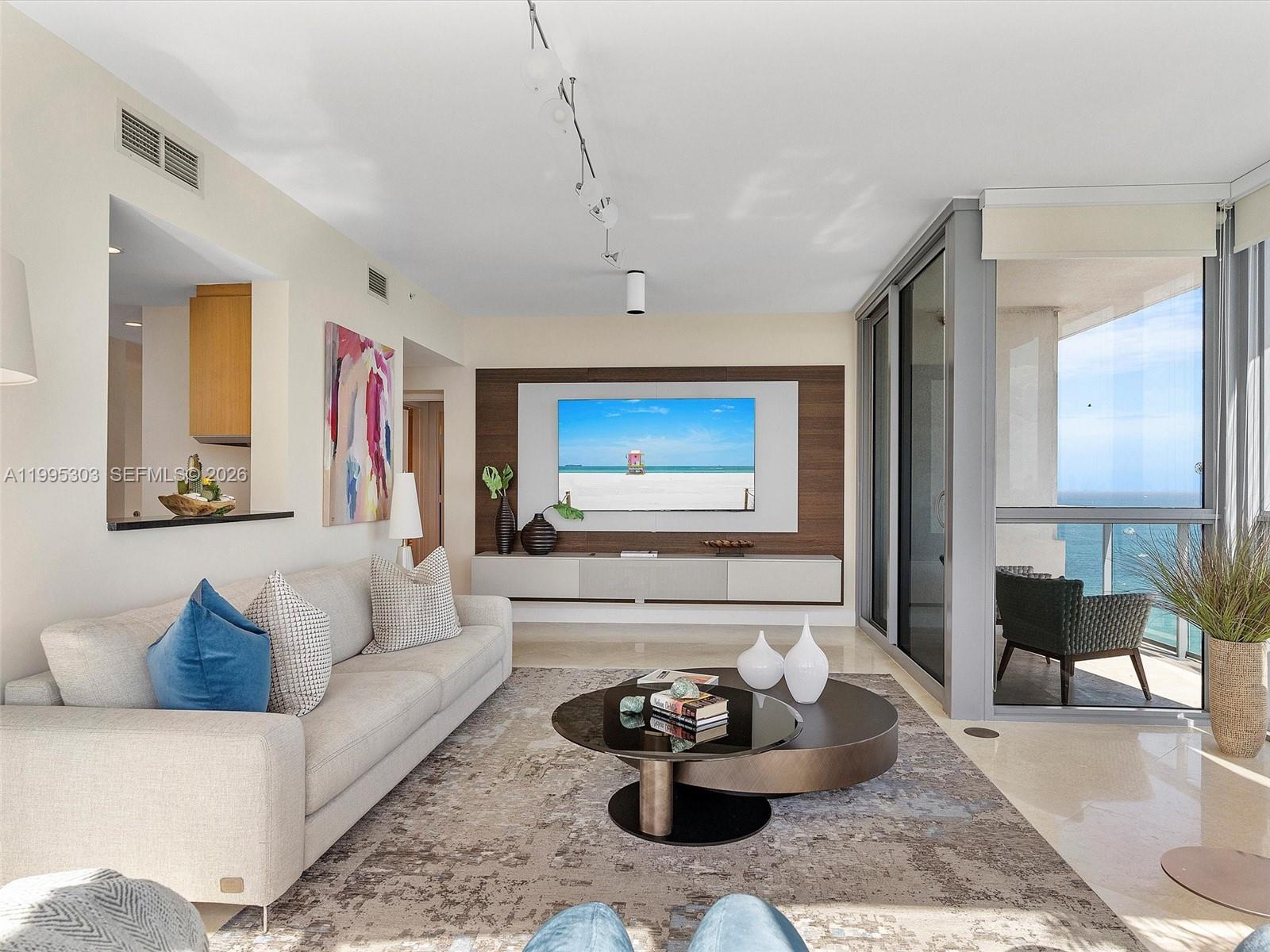 A modern living room features a wall-mounted television, a neutral sofa, and a balcony view — 101 20th St # 3002, Miami Beach FL 33139, MIAMI BEACH, FL