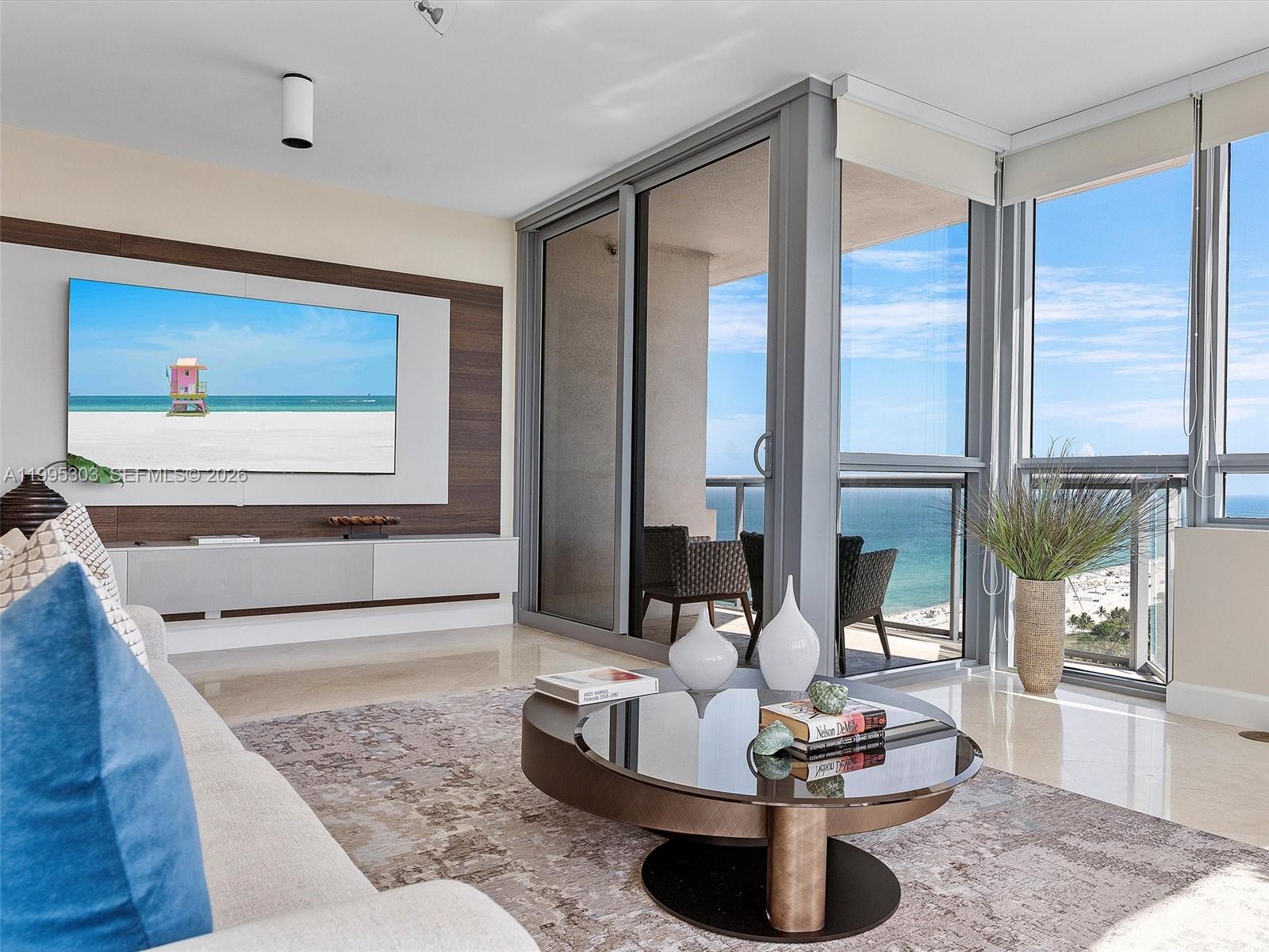 A modern living room features a wall-mounted television, a circular coffee table, and balcony views — 101 20th St # 3002, Miami Beach FL 33139, MIAMI BEACH, FL